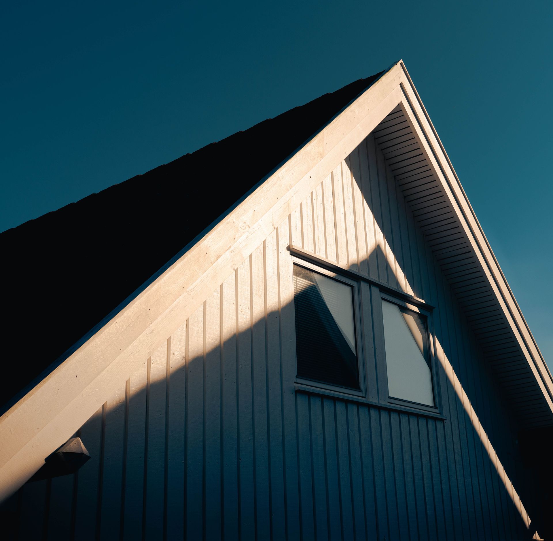 A modern house roof illuminated by sunlight casting artistic shadows.
