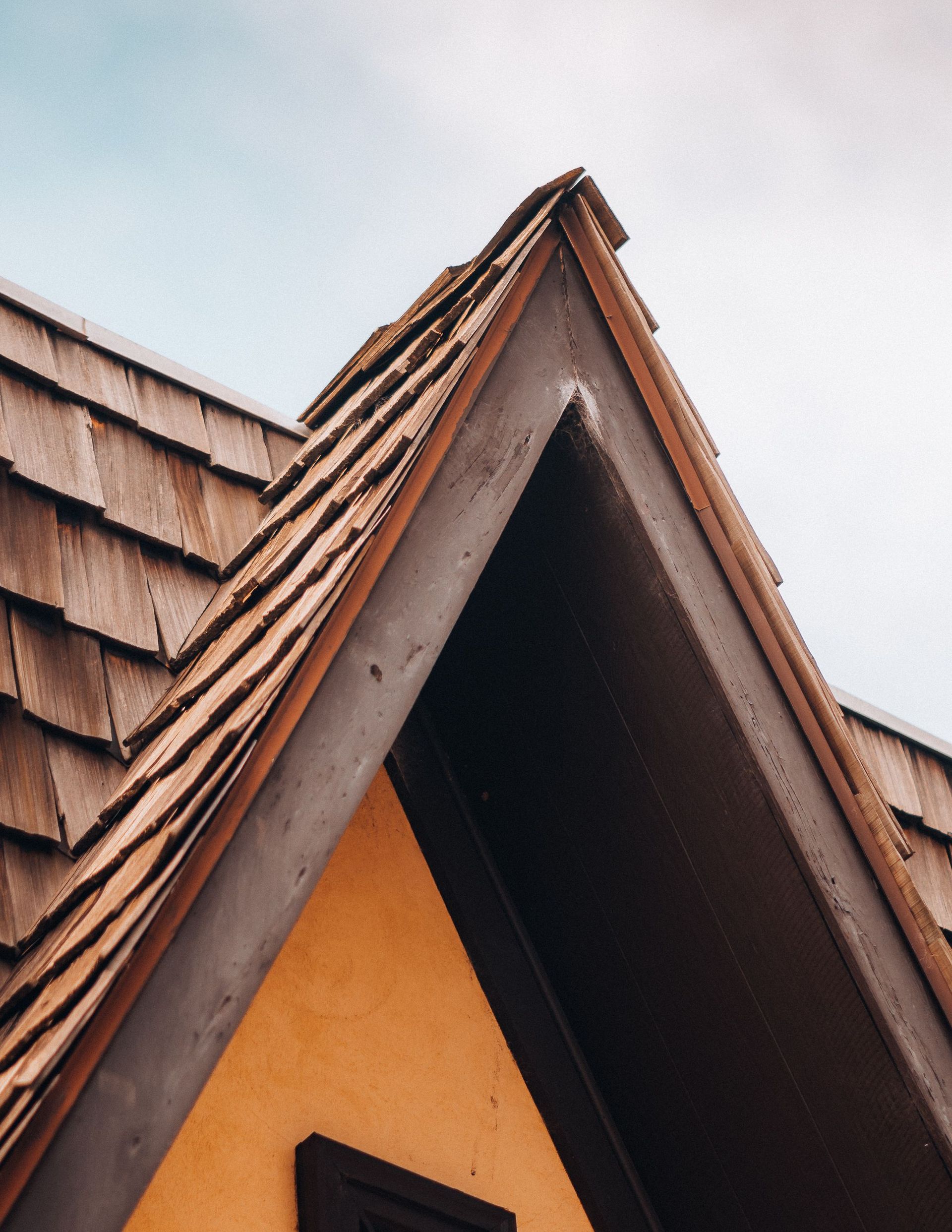 Detailed shot of a gable roof with rustic wooden shingles, showcasing architectural detail.
